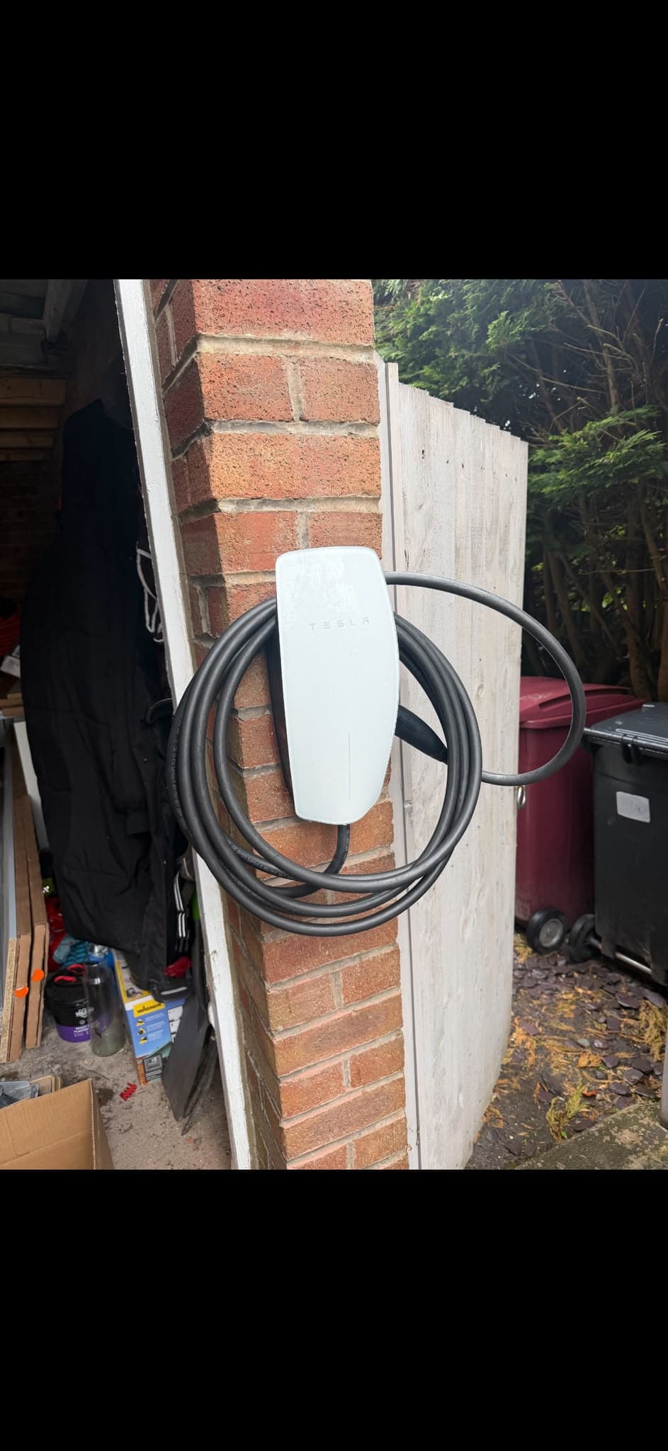 Wall-mounted home EV charger freshly installed on brick